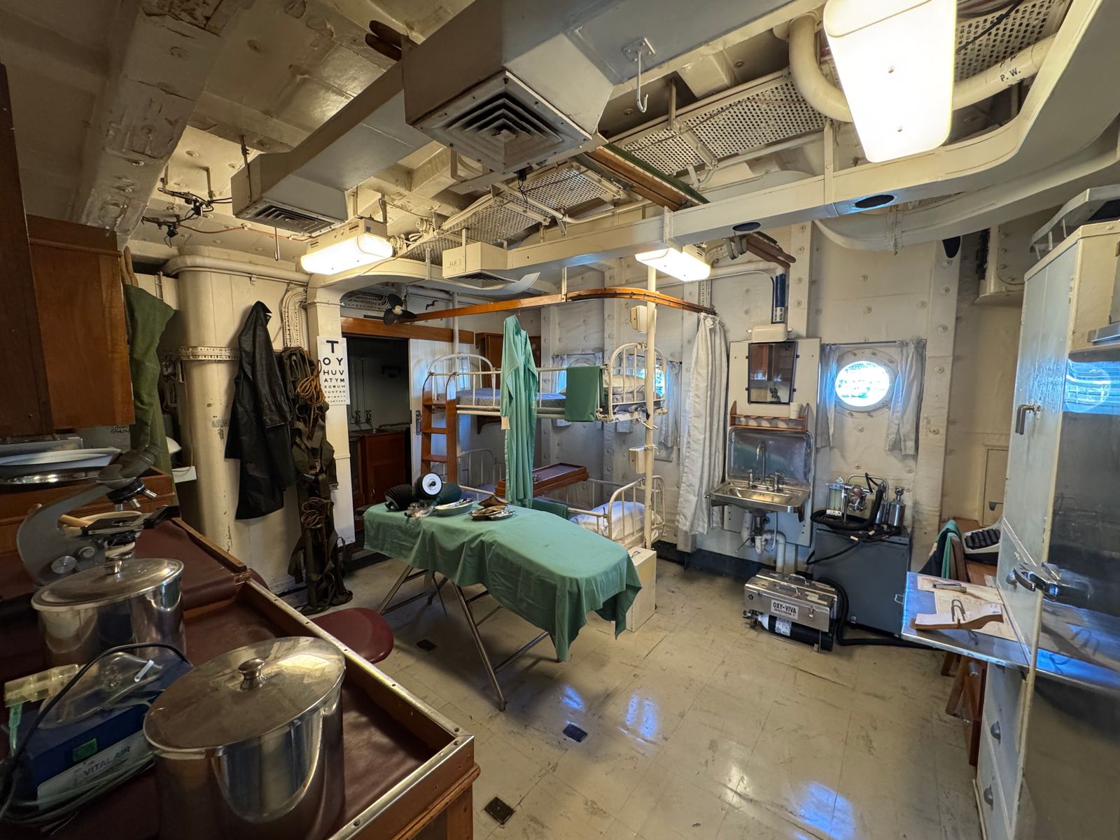 Detailed view of a vintage naval ship hospital room with medical equipment and bunk beds.