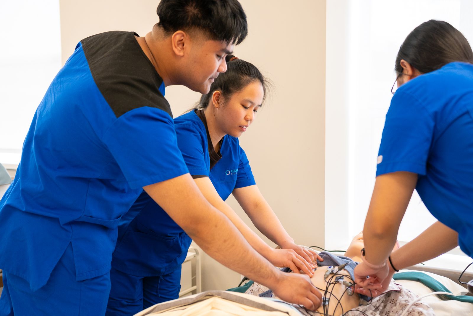 Free Nursing students practice using a medical mannequin in a simulation lab, focusing on patient care techniques.