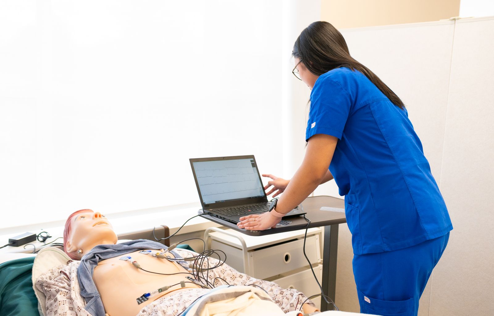 Free Nursing students practice using a medical mannequin in a simulation lab, focusing on patient care techniques.