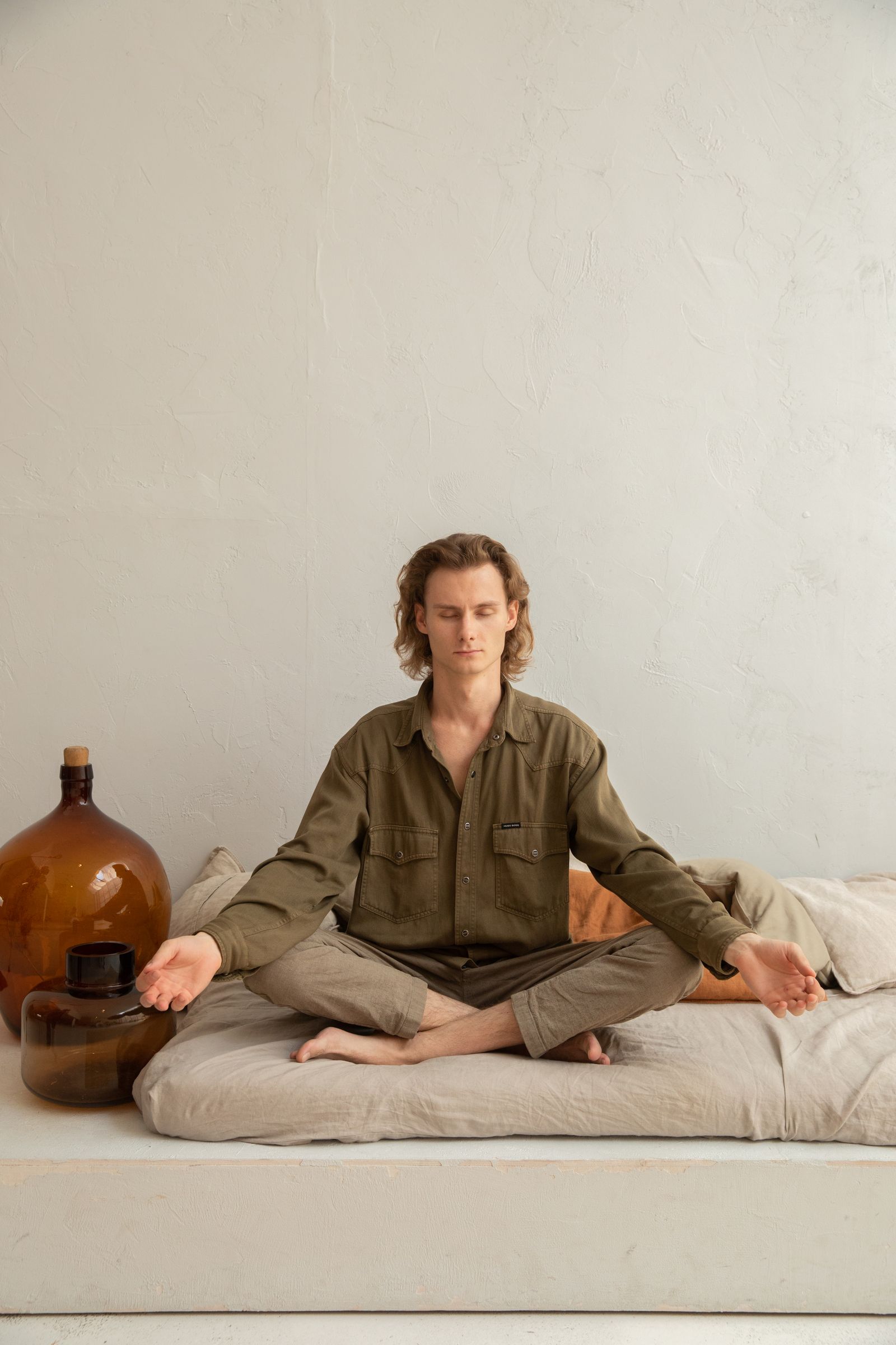 Young man meditates in lotus pose, indoors, embodying peace and mindfulness.