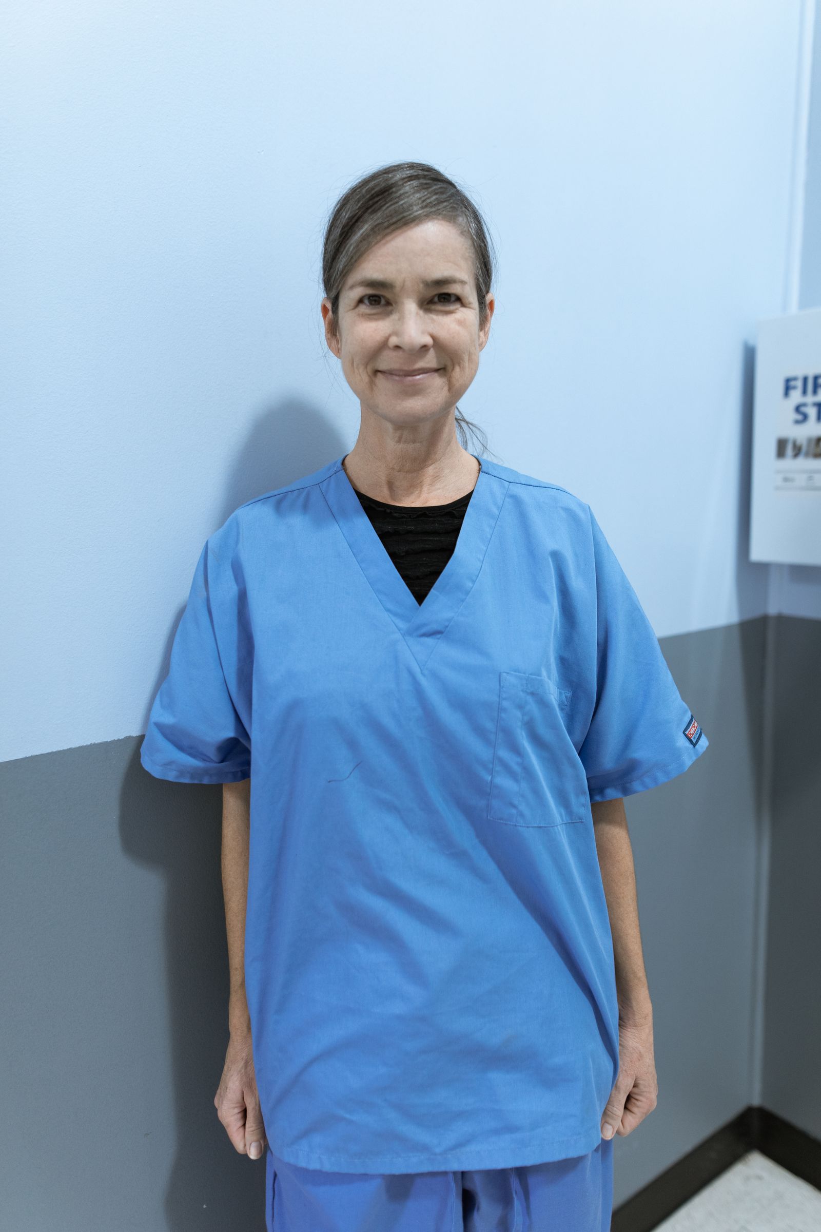 Free to use Portrait of a smiling elderly female nurse in a hospital setting wearing blue scrubs.