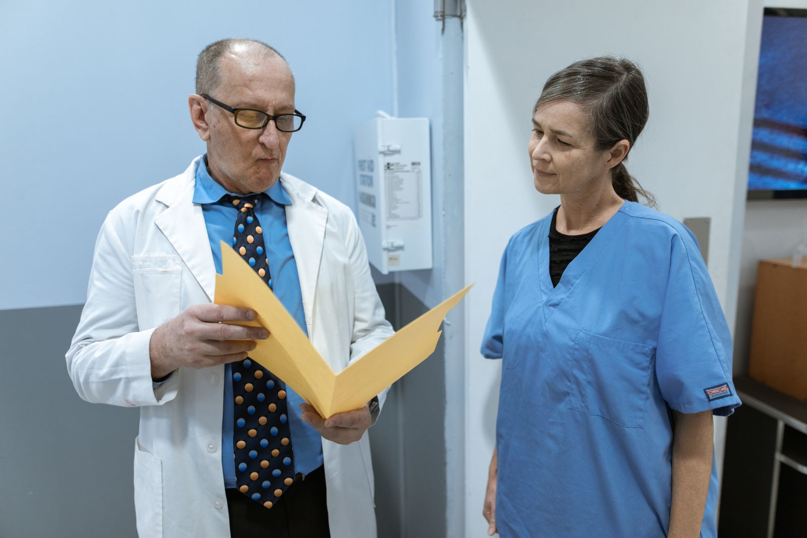 Free Doctors discussing at a medical clinic. Healthcare team collaboration.Free Doctor and nurse in hospital corridor engaging in discussion about patient information and treatment.