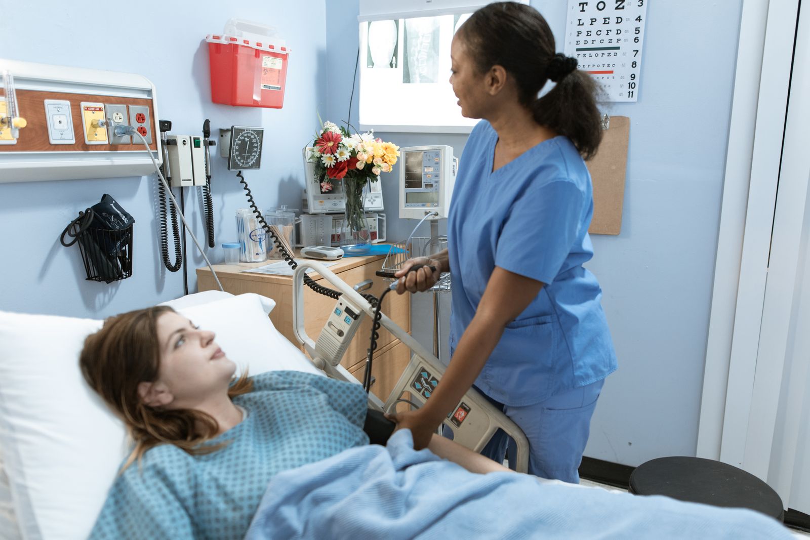 Free Nurse providing care to a patient in a hospital room with medical equipment.