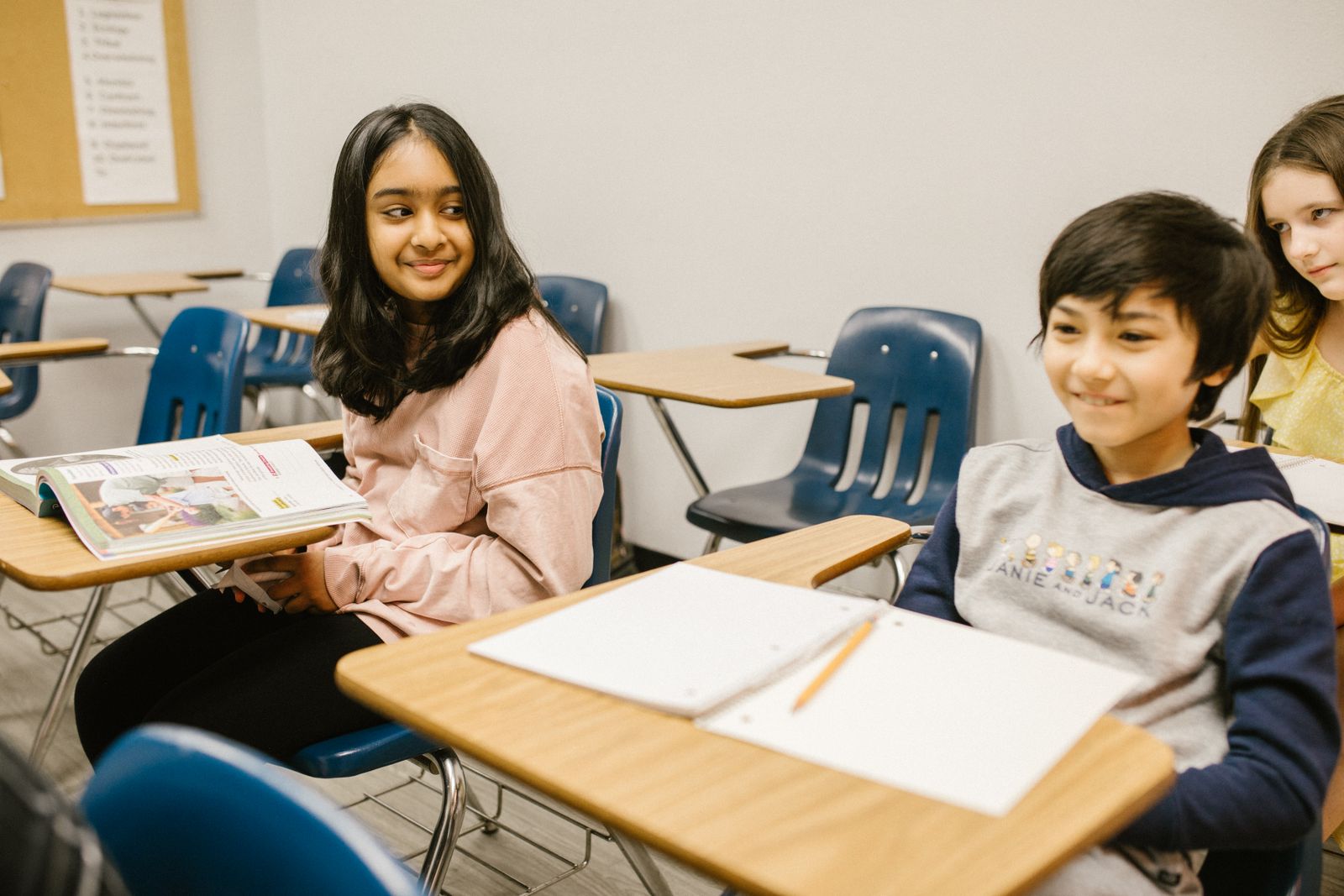 Free Students smiling and interacting in a cheerful classroom setting, fostering education and cultural diversity. Stock Photo.