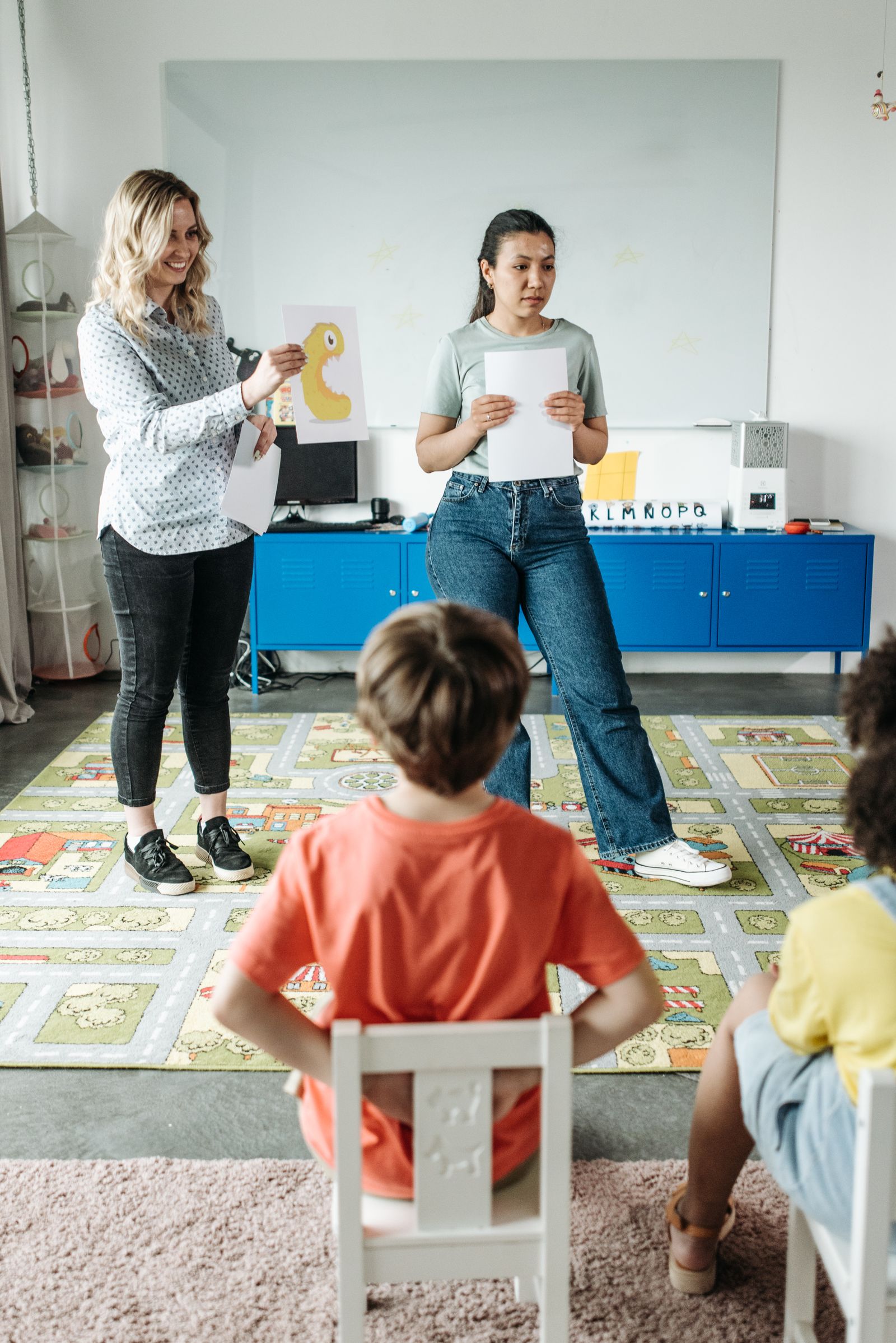 Free Teacher instructing students in classroom setting during pandemic, showcasing diverse learning.Free Teacher interacts with a group of young students in a vibrant classroom setting, using a globe for educational activities.